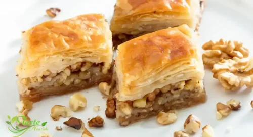 Pouring cold honey syrup over hot baklava phyllo pastry for perfect absorption
