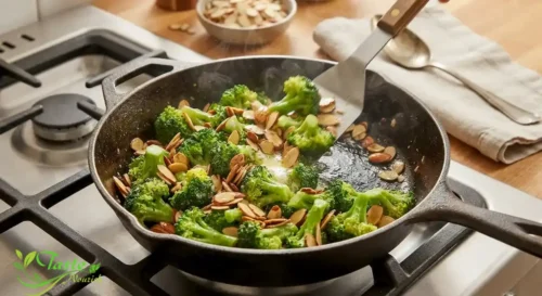 Steamed broccoli florets being tossed with toasted almonds and butter in a skillet