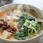 Warming Ginger Miso Soup Recipe (Easy, 40 Minutes) Steaming bowl of ginger miso soup with tofu, mushrooms, carrots, spinach, and sliced scallions