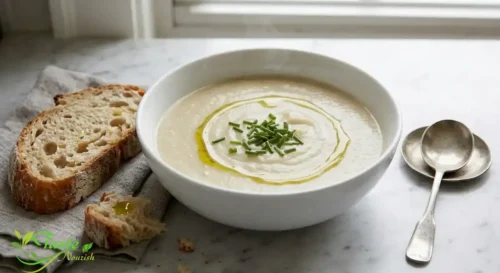 Bowl of velvety roasted garlic soup with crusty bread